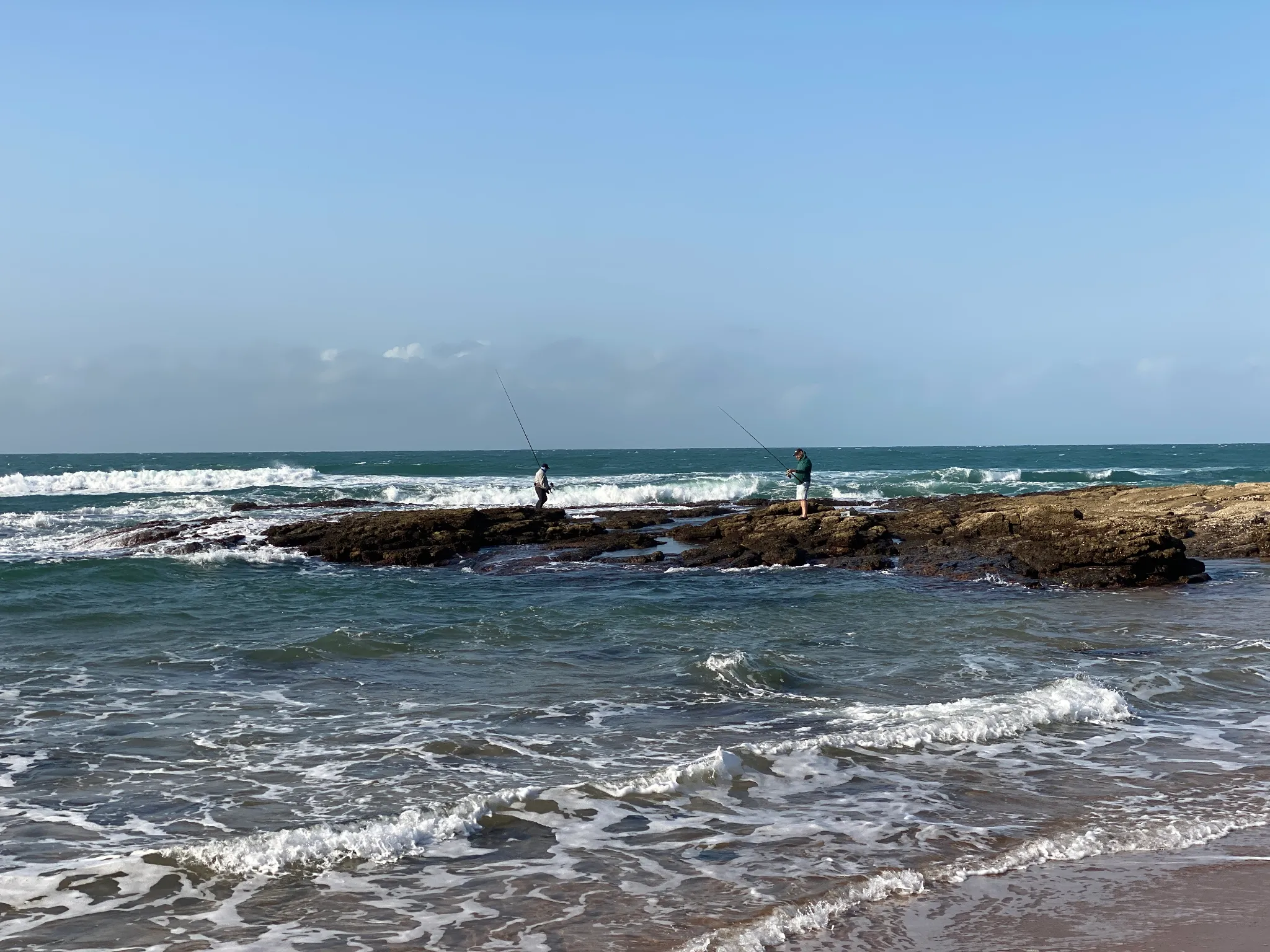 Two fishermen on rocks in the ocean surf at Zinkwazi.