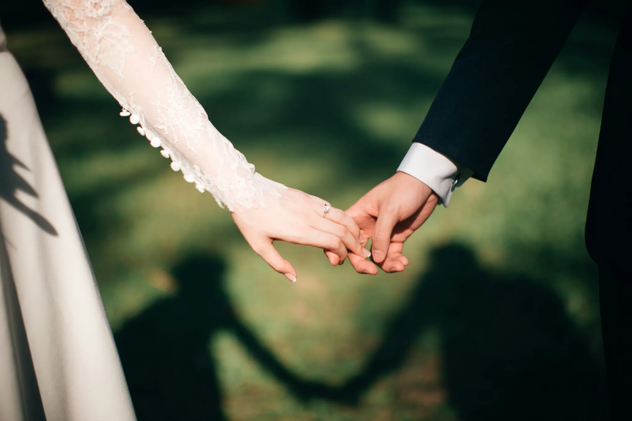 A newlywed couple holds hands, the bride wearing an engagement ring, celebrating their wedding day in Ballito.