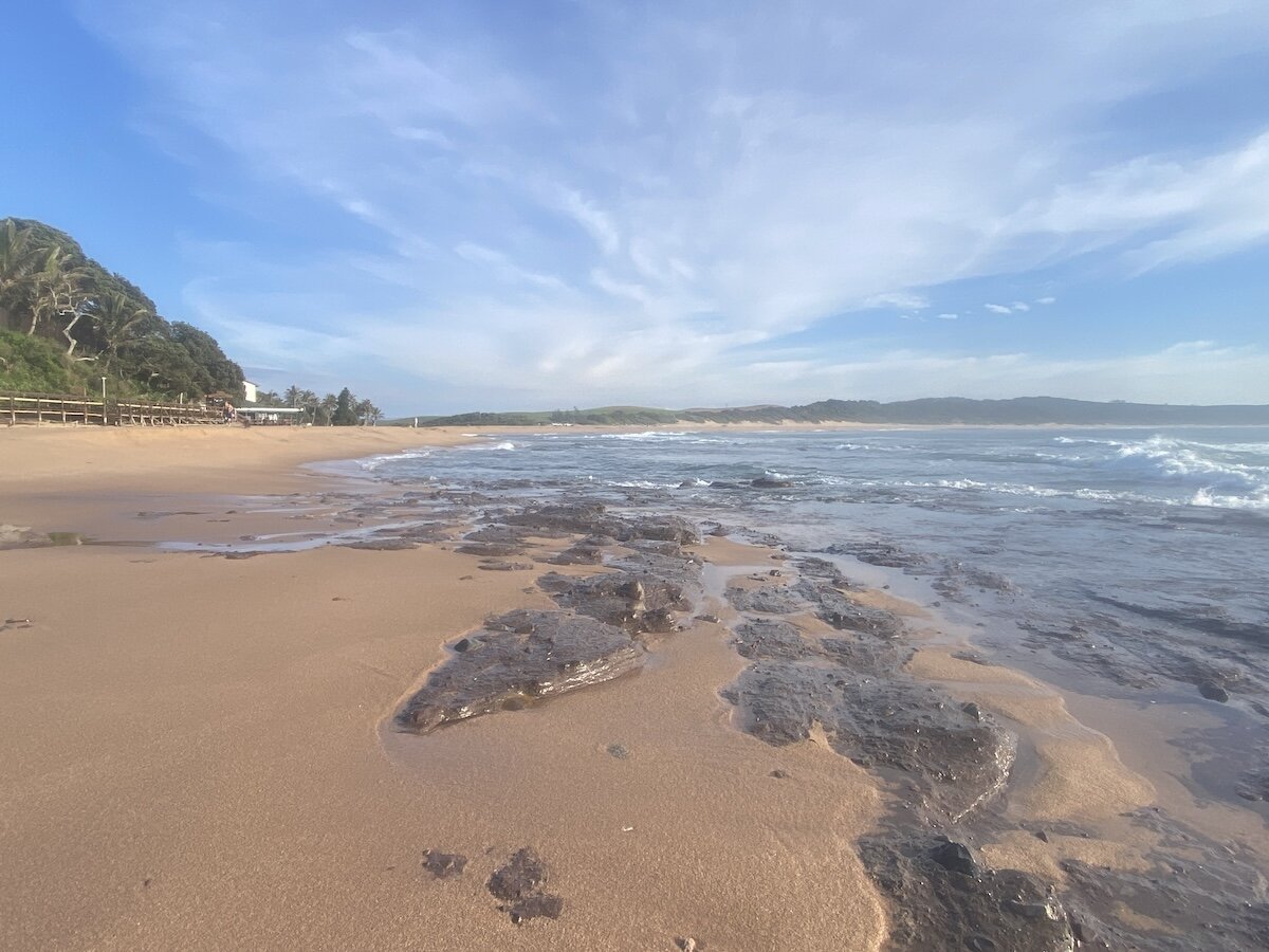 Rocky shallows exposed at low tide along Zinkwazi beach with the boardwalk in the background