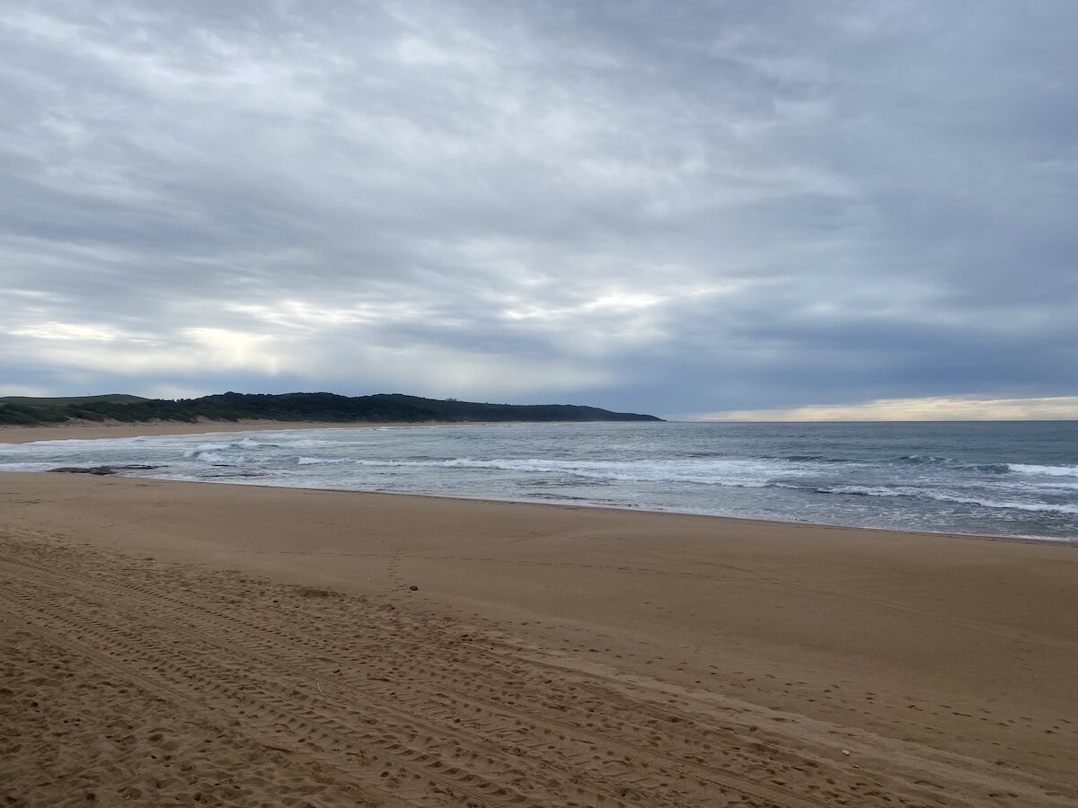 Quiet overcast winter morning on an empty Zinkwazi beach with soft waves and grey skies