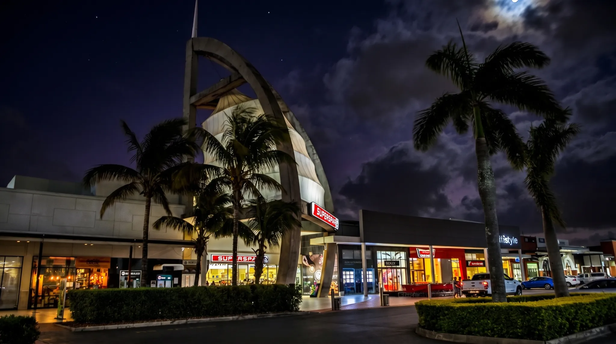 Night scene of a modern retail center with a full moon and palm trees in Ballito.