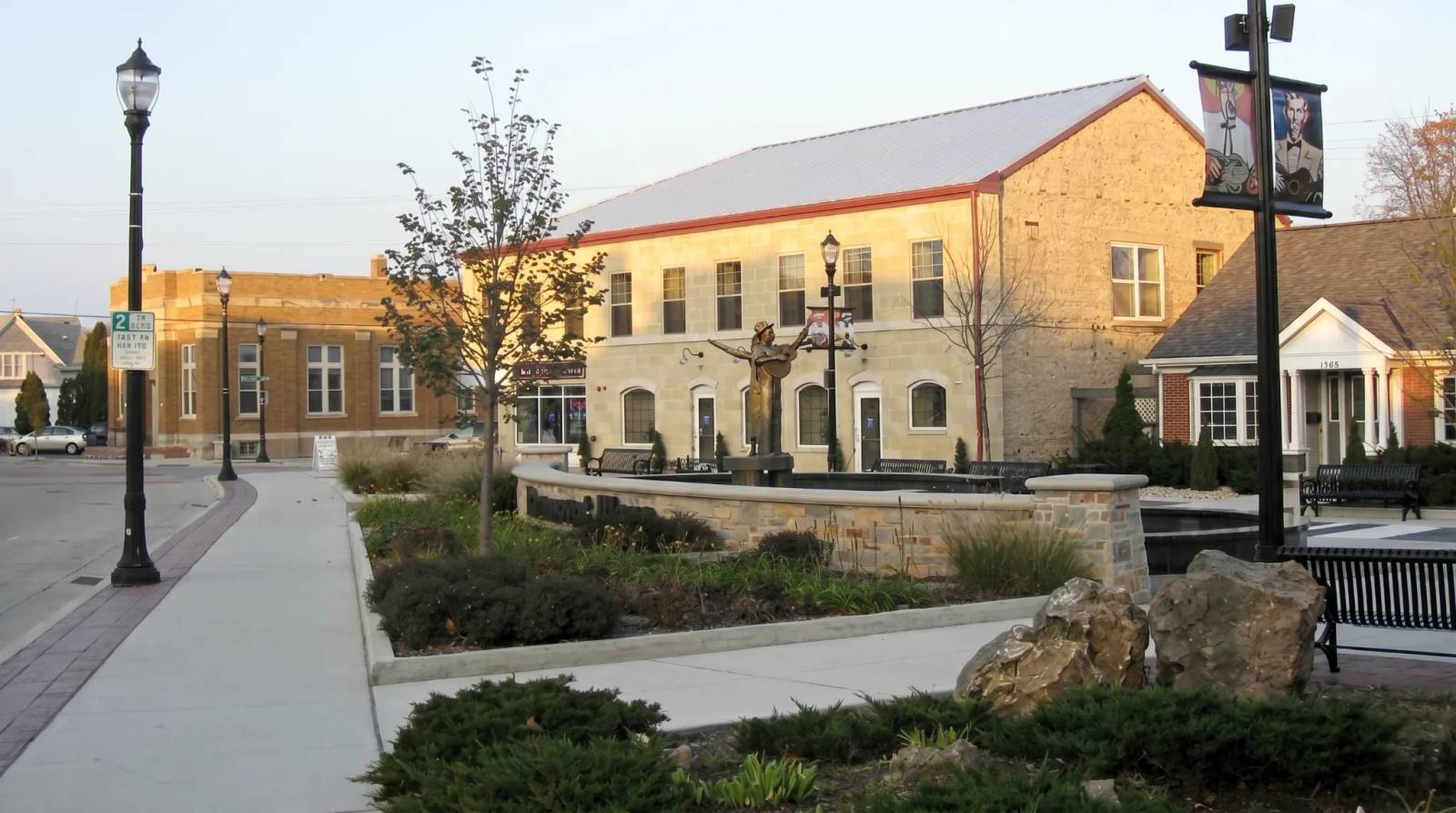 A public plaza with a statue and stone buildings under a clear sky in Grafton.