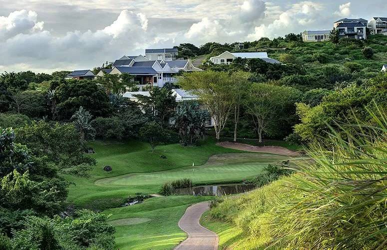 Golf green with a winding path and houses nestled in lush hills in New Guelderland.
