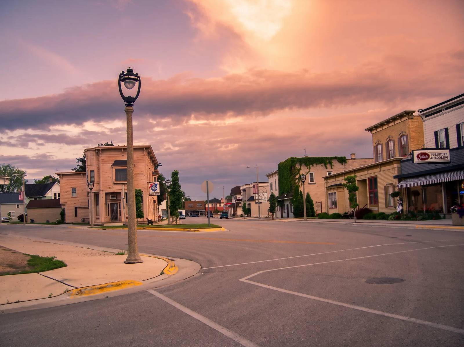 Downtown New Holstein, Wisconsin at golden hour, with a lamppost and historic storefronts.