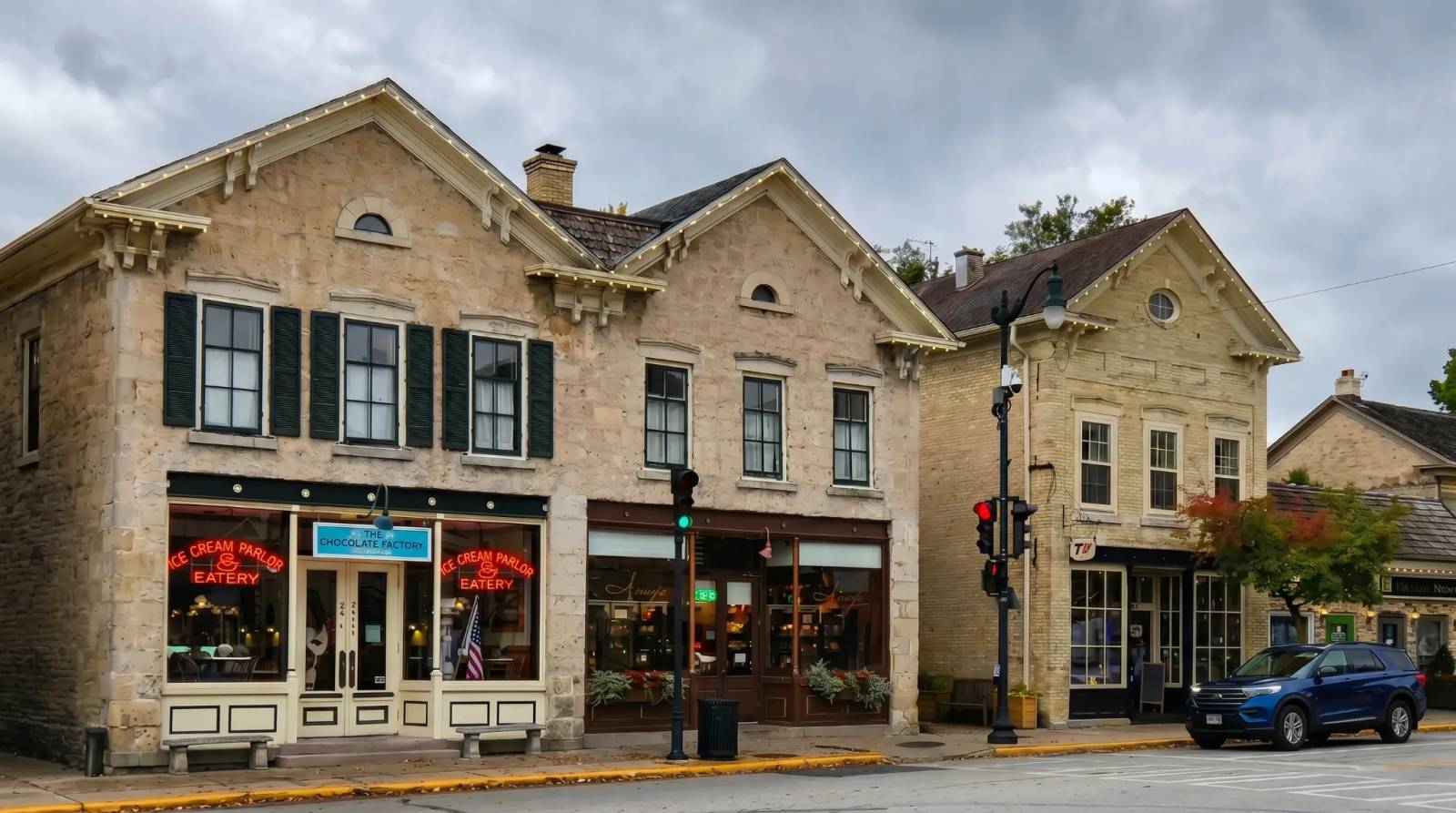 Historic buildings with storefronts along a street in Cedarburg, under a cloudy sky.