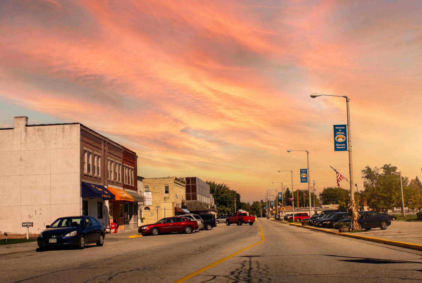 Historic downtown Milton, Wisconsin at sunset, with brick storefronts and welcome banners.
